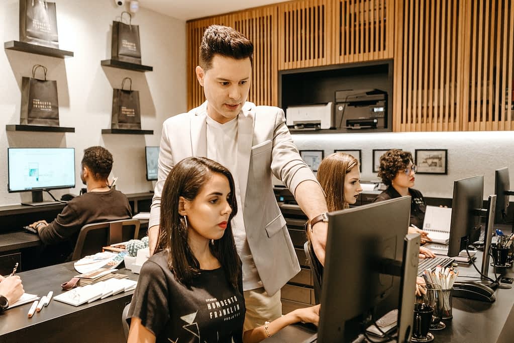 Man teaching a female receptionist in front of a computer