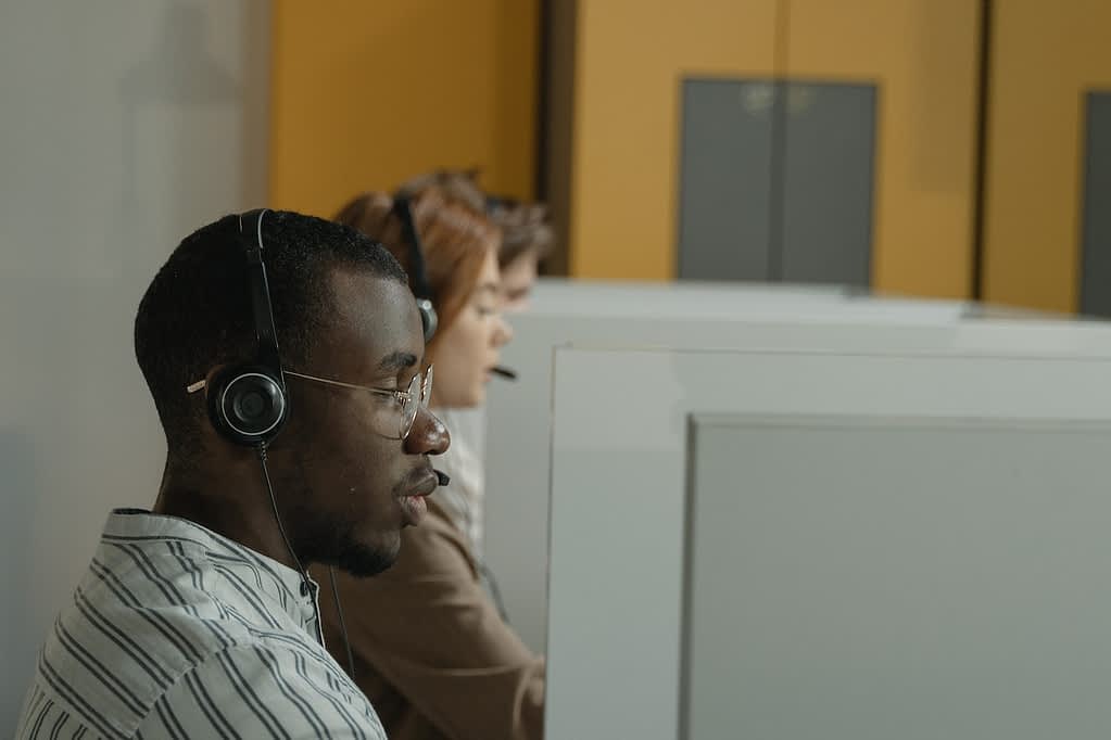 Male virtual receptionist speaking with a client while looking at a computer screen.