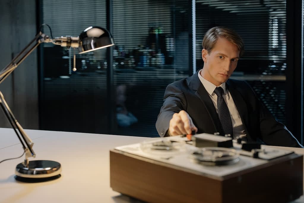 Man sitting at table and using tape recorder.