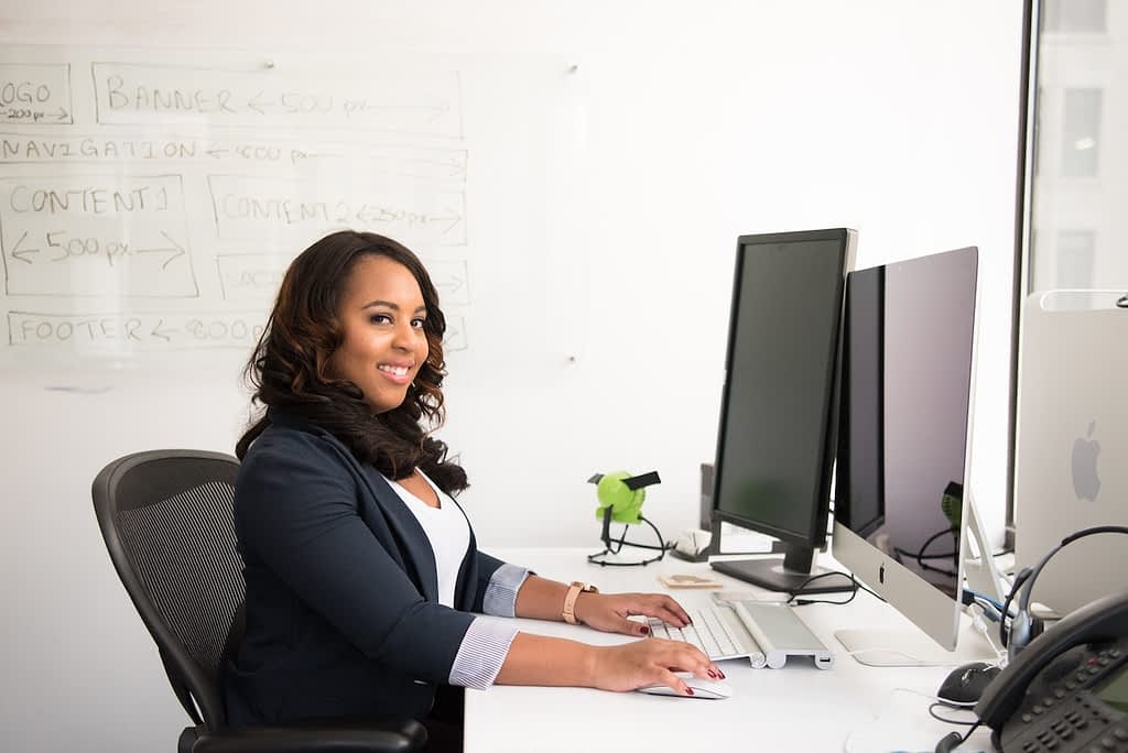 Woman smiling and facing a computer screen.