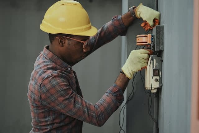 Electrician fixing electrical wires in a junction box.